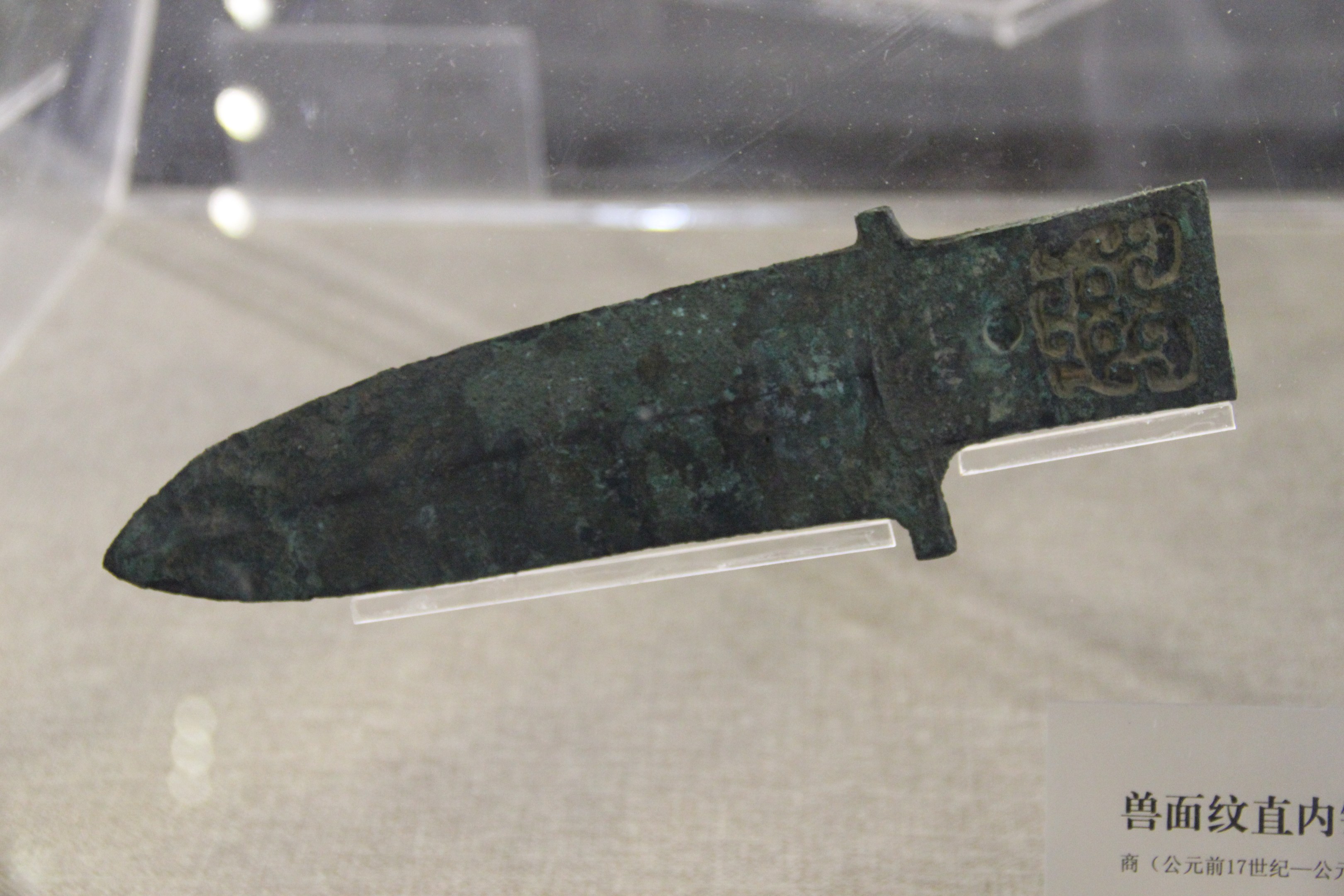 Ein Messer in einer Glasvitrine mit einer Texttafel darunter.