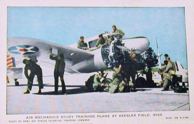 Gruppe von Menschen um ein Trainingsflugzeug auf einer Landebahn mit einem klaren blauen Himmel im Hintergrund, Text unten lautet "Air Mechanics Study Training Plane at Keesler Field, Miss."