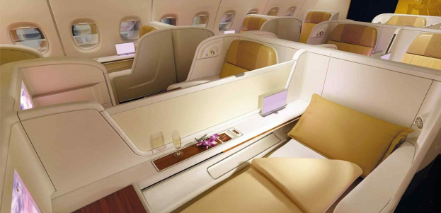 Innenraum einer Singapore-Airlines-A380-Business-Class-Kabine mit Sitzreihen, einem Tisch mit einer Blumenvase und Gläsern sowie Fenstern auf beiden Seiten.