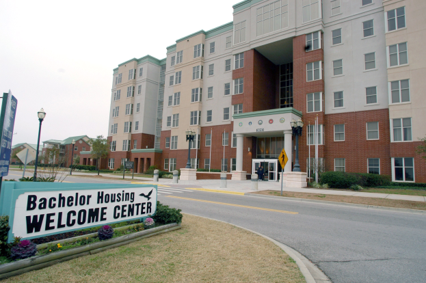 Außenansicht eines Bachelor-Unterkunfts-Willkommenszentrums mit Gebäuden, Straßeninfrastruktur, Fahrzeugen, Grünflächen und einem klaren Himmel.