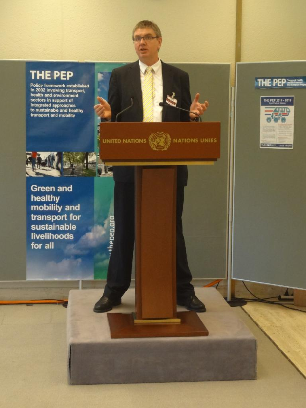 Eine Person steht an einem Podium mit einem Banner vor einer Wand.