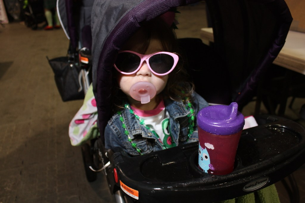 Ein Kind sitzt in einem Gehwagen auf der Straße.