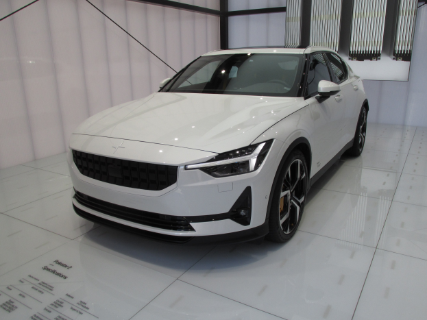 Weißer Polestar 1 Elektroauto in einer Ausstellungshalle zu sehen, mit einem schlanken, modernen Design mit glänzender Lackierung, hellen, winkligen Scheinwerfern, einer langen Motorhaube, einem tiefen Körper, großen sportlichen Rädern und einem geräumigen luxuriösen Innenraum mit Ledersitzen und einem modernen Armaturenbrett.