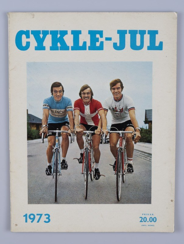 Drei Menschen auf Fahrrädern auf einer Straße mit Häusern, Bäumen und einem klaren blauen Himmel, mit dem Text "Cykle-Jul 1973 - Cyclocross Magazine" oben und unten.