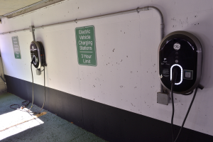 Eine Ladesäule für Elektrofahrzeuge in einer Tiefgarage, mit zwei an der Wand montierten Ladesäulen und Informationsschildern darüber.