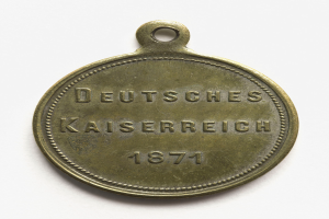 Eine Bronzemedaille mit der Inschrift "Deutsches Kaiserreich 1871" auf einem weißen Hintergrund.
