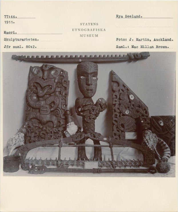 Ein Schwarz-Weiß-Foto einer kunstvoll geschnitzten Skulptur mit Text darauf, das in einem Museum ausgestellt ist.