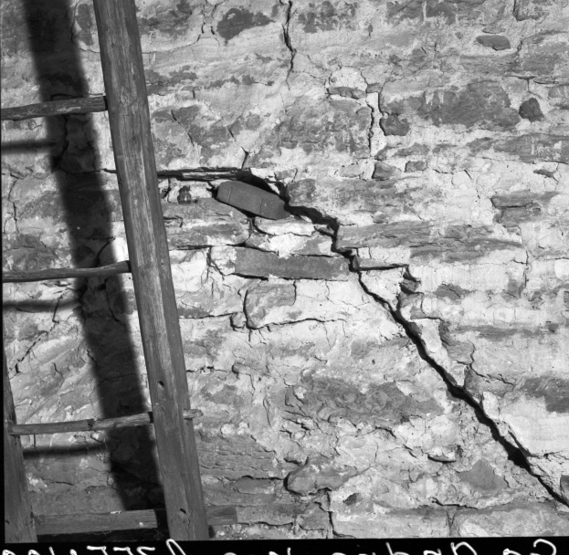 Ein Schwarz-Weiß-Foto einer Leiter, die an einer Wand lehnt und einen Riss hat, mit Text unten.