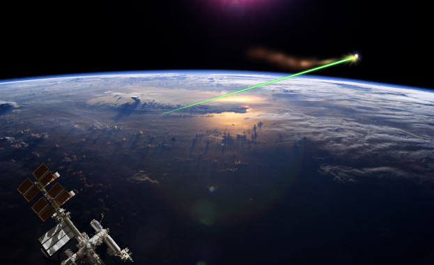 Satellit in der Erdumlaufbahn mit einem hellen Laserstrahl, der den dunklen Himmel erleuchtet.
