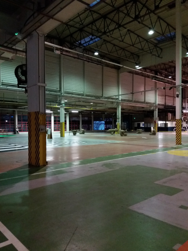 Ein großer Lagerraum voller verschiedener Maschinen, einschließlich Metallstangen und Lampen, mit Text auf dem Boden auf der rechten Seite.