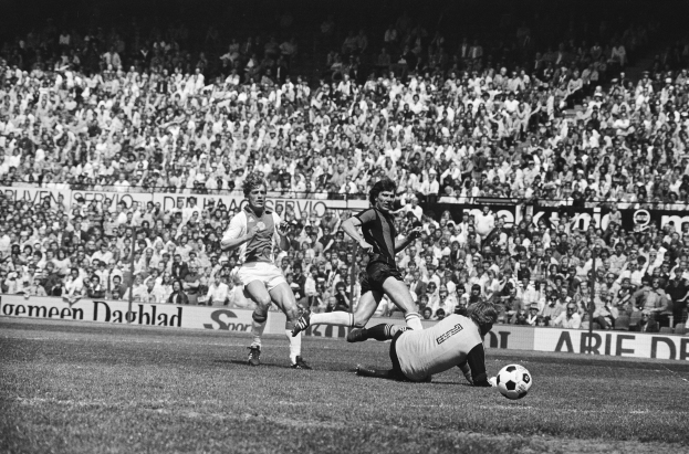 Schwarzes und weißes Foto von Fußballspielern im Einsatz auf einem Feld mit Zuschauern im Hintergrund und einem Bundesliga-Banner 1978-79 mit der Aufschrift "Ajax 1-1 Hannover 96."