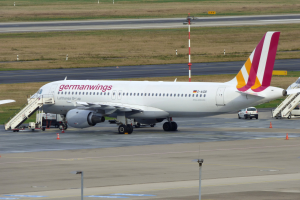 Ein Germanwings Airbus A320-200-Flugzeug auf dem Frankfurter Flughafen geparkt, mit Fahrzeugen, Verkehrskegeln, Pfählen und Gras im Hintergrund.