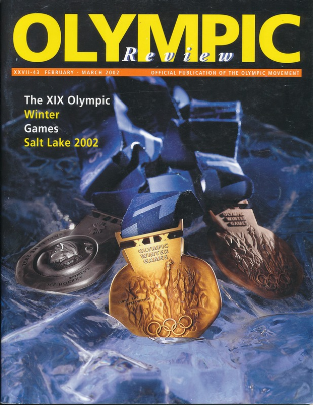 Ein Buch mit dem Titel "Olympische Spiele-Revue" mit mehreren Medaillen in verschiedenen Größen und Farben und fetter Schrift auf dem Cover.
