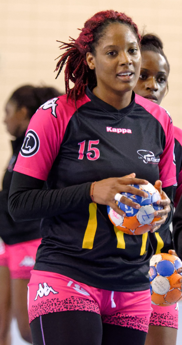 Eine Gruppe von Frauen, die zusammenstehen und jeweils einen Fußball halten, wobei die mittlere Frau ein weißes T-Shirt und blaue Shorts trägt und eine Pferdeschwanzfrisur hat.