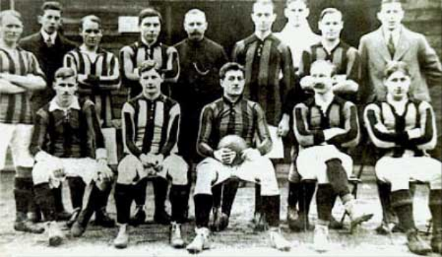 Ein Schwarz-Wei├č-Foto einer Fu├čballmannschaft, mit einigen stehenden und einigen sitzenden Spielern vor einer Wand, mit dem Text "Ballymena Football Club" unten.