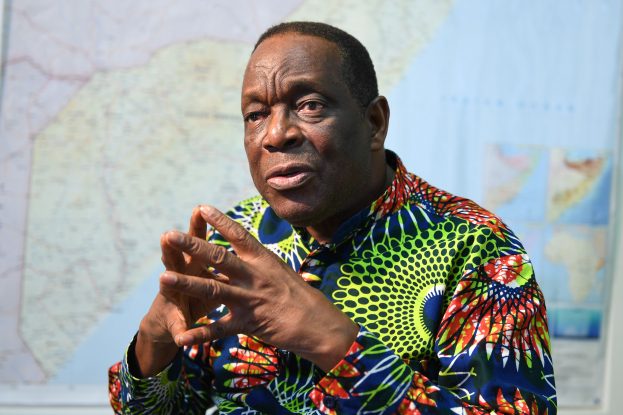 Ein Mann in einem bunten Hemd sitzt an einem Tisch mit einer Karte im Hintergrund und sieht besorgt aus, möglicherweise wegen Arbeitslosigkeit.