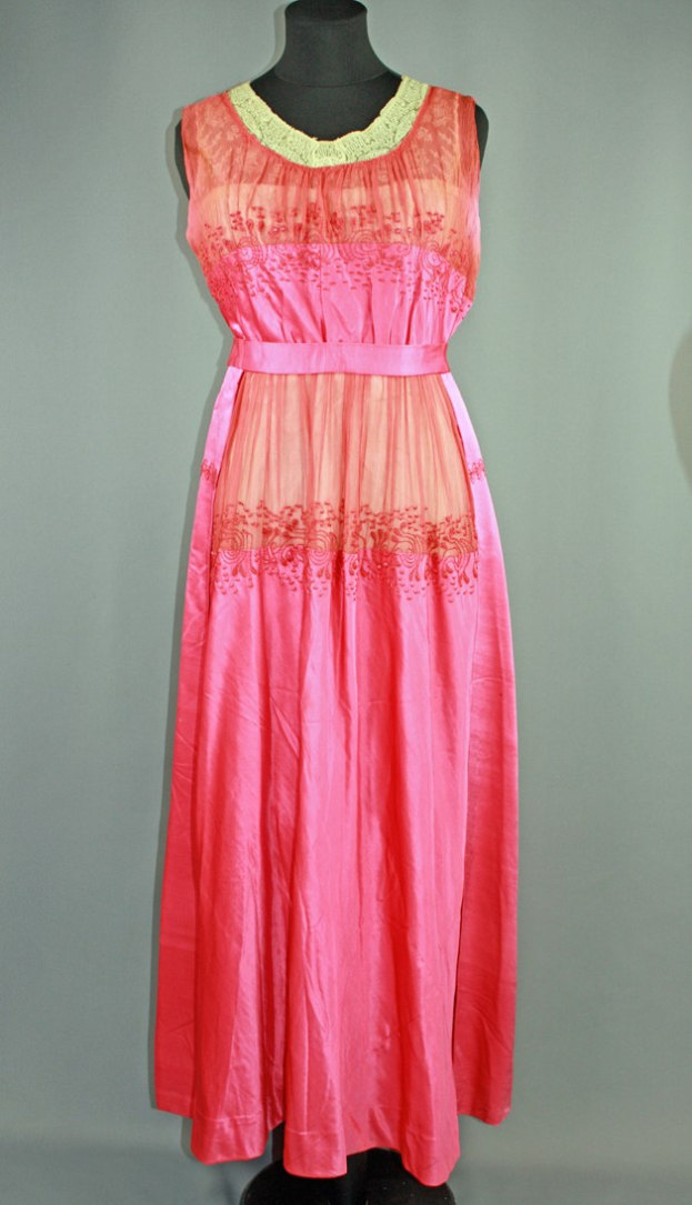 Eine Schaufensterpuppe trägt ein pinkes Nachthemd mit feiner Spitzenverzierung, das eine volle, bis zum Boden reichende Schleppe hat.