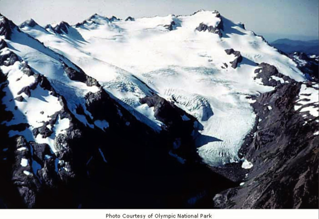 Ein majestätischer Berg mit einem großen zentralen Gletscher, umgeben von schneebedeckten Gipfeln unter einem klaren blauen Himmel, mit Text am unteren Rand des Bildes.