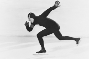 Ein Schwarz-Weiß-Foto eines Eisschnellläufers mit Handschuhen, der auf dem Eis fährt.