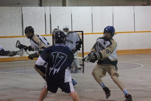 Menschen in Helmen mit Stöcken scheinen in einem Innenraum zu kämpfen, mit einem Netz im Hintergrund.