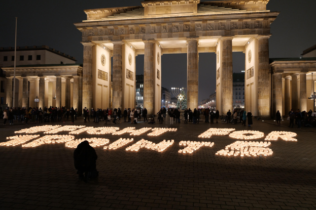 Eine Gruppe von Menschen vor dem beleuchteten Reichstagsgebäude in Berlin, Deutschland, mit der Aufschrift 'Kampf für Freiheit' im Vordergrund.