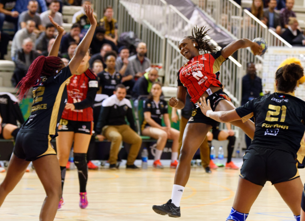 Eine Gruppe von Frauen spielt Volleyball auf einem Feld mit Zuschauern im Hintergrund.