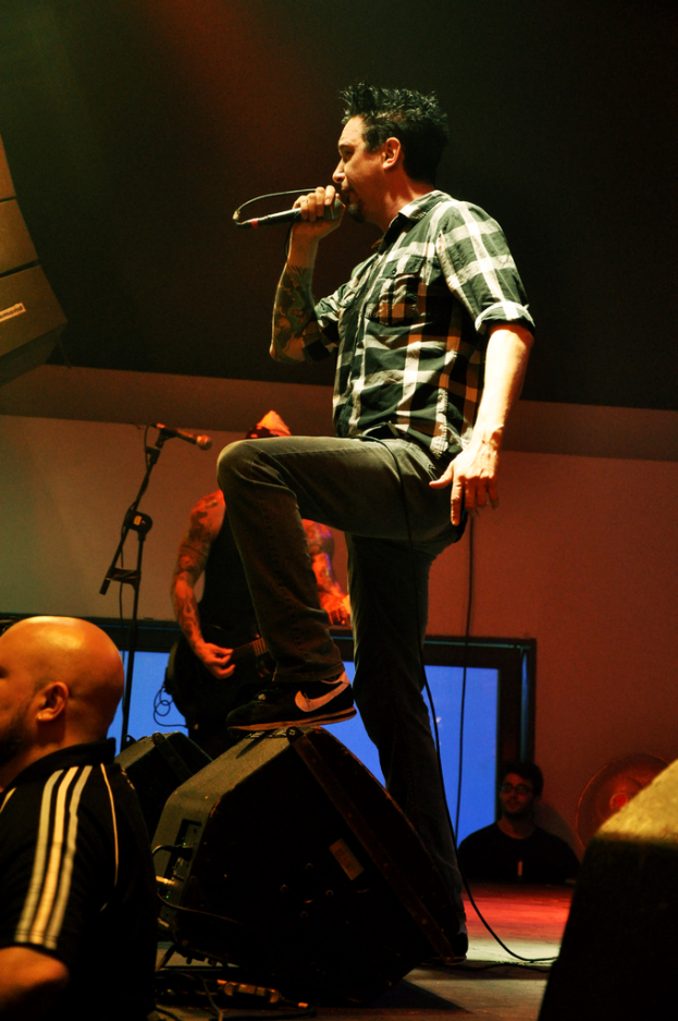 Eine Person steht auf der Bühne und hält ein Mikrofon in der Hand und singt, während eine andere Person links auf dem Boden steht.