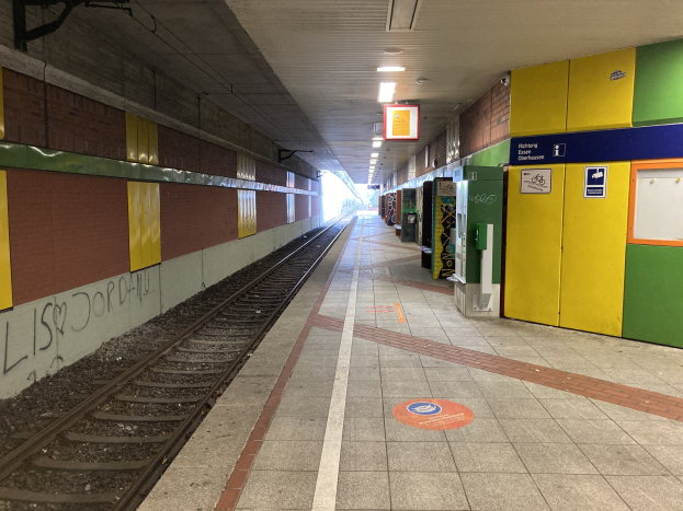 Ein Bahnhof in Berlin, Deutschland, bekannt als Berlin Hauptbahnhof, mit einem Zug auf den Schienen unter Deckenleuchten, Graffiti an einer linken Wand und einigen Gegenständen auf der rechten Seite.
