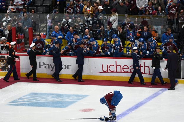 Hockeyspieler auf dem Eis umgeben von Teamkollegen und Gegnern, mit Zuschauern im Hintergrund bei einem Spiel der Colorado Avalanche gegen die San Jose Sharks am 24. März 2015.