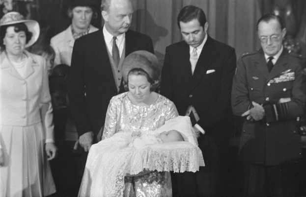 Königin Elizabeth II. wiegt ihren neugeborenen Sohn Prinz Philip, während Prinz Philip, Herzog von Edinburgh, neben ihnen in formeller Kleidung steht.
